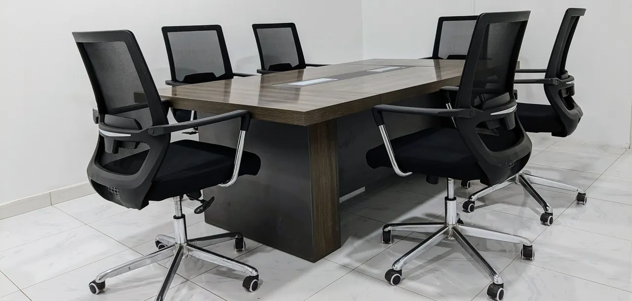 Sala de juntas con mesa de madera rectangular y seis sillas de oficina negras